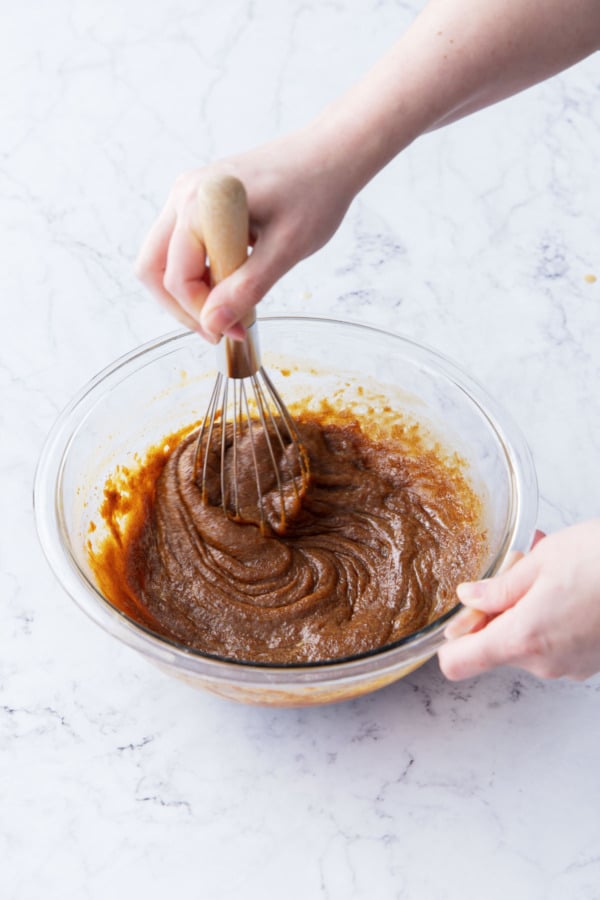 Whisking eggs into batter until very smooth and emulsified.