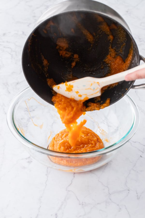 Transferring reduced persimmon puree into a mixing bowl.