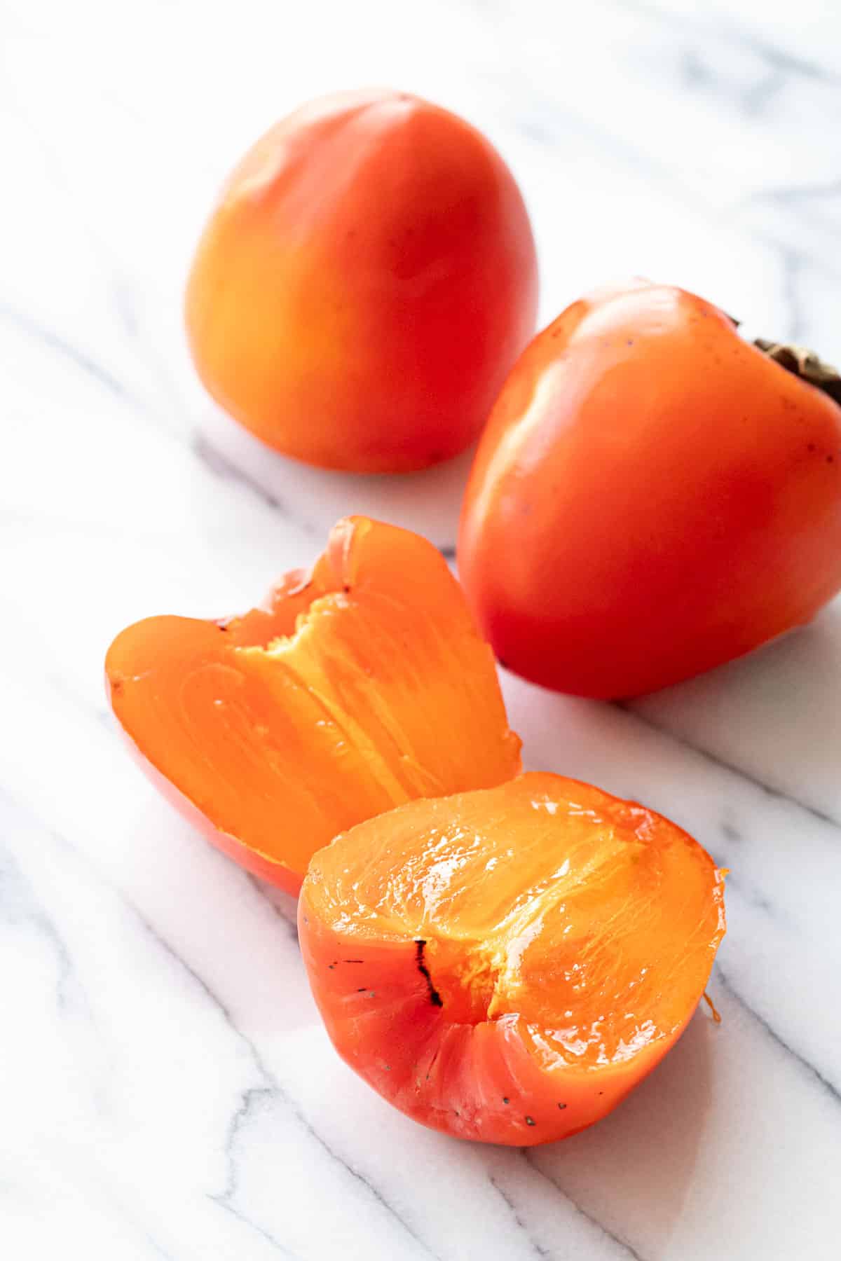 Ripe hachiya persimmons, one cut in half to show the custardy texture.