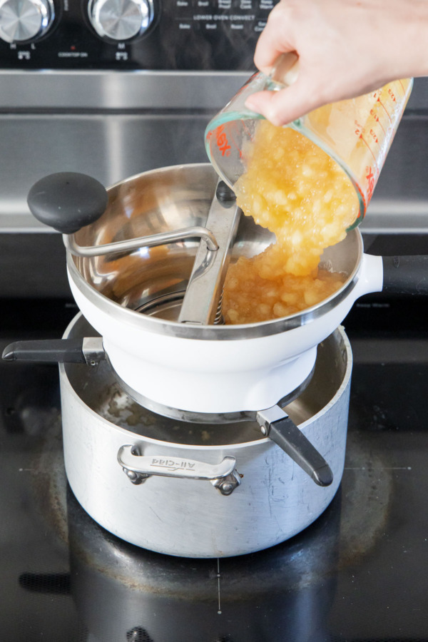 Running cooked apples through a food mill set over the saucepan still on the stove.