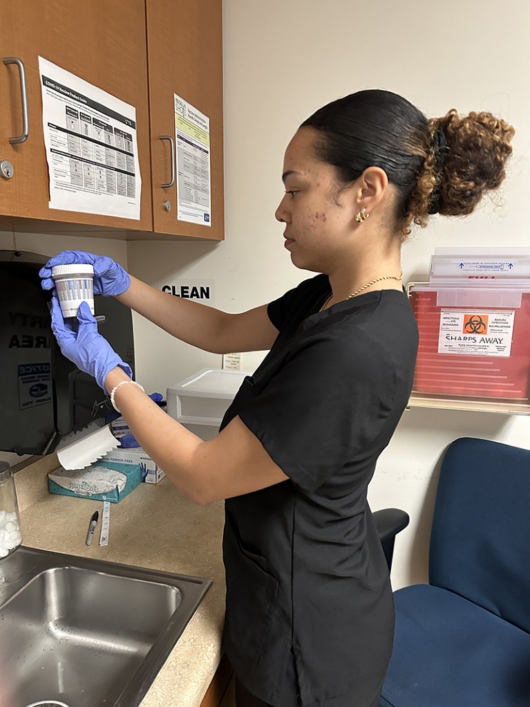 Arrianna Lister wears gloves and holds a drug screening urine sample