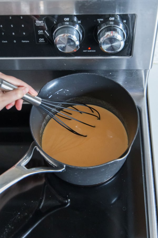 Whisking milk and pumpkin puree in a saucepan on the stovetop.