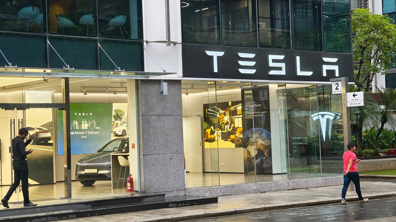 Picture of tesla showroom in Mumbai illuminated glass facade, pedestrians passing b