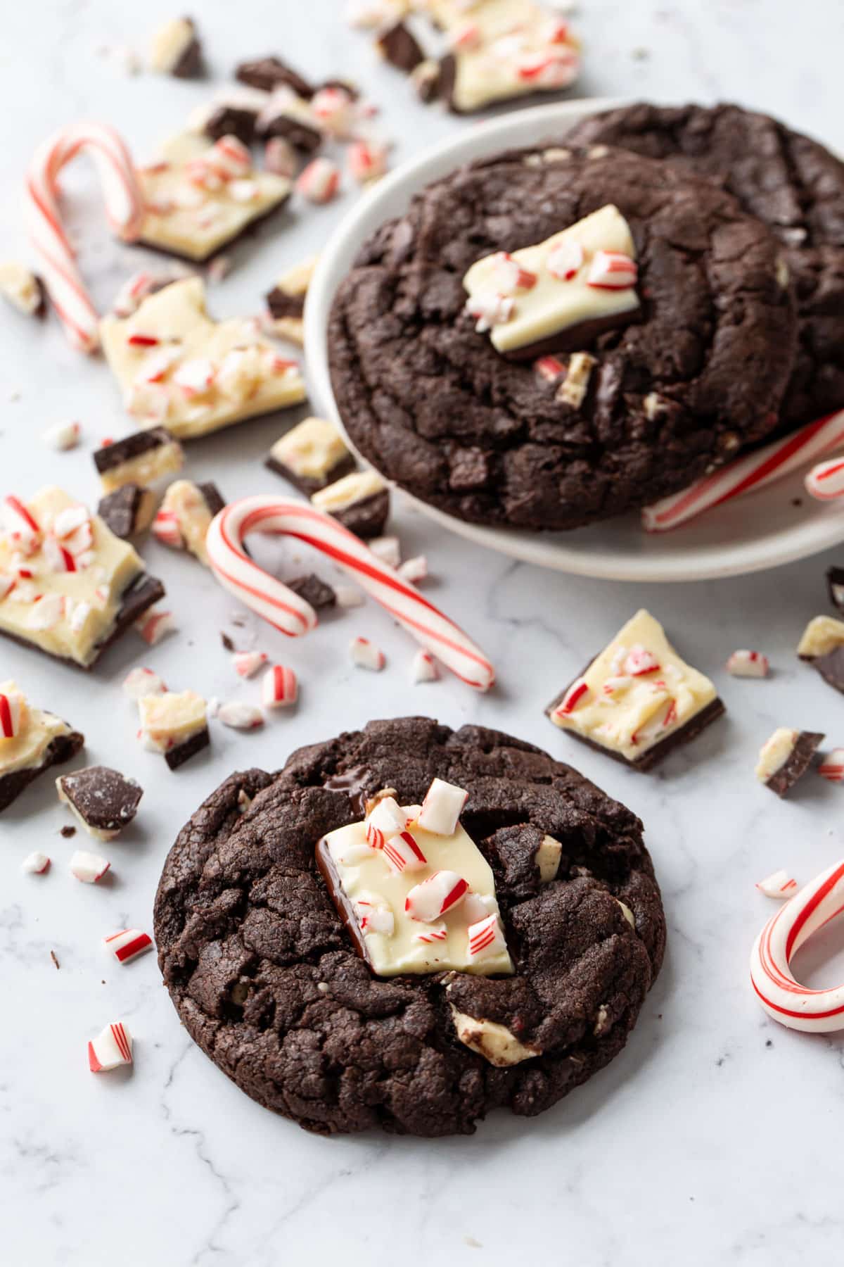 Chocolate Peppermint Bark Cookies on a marble background, with candy canes and broken bits of peppermint bark scattered around.