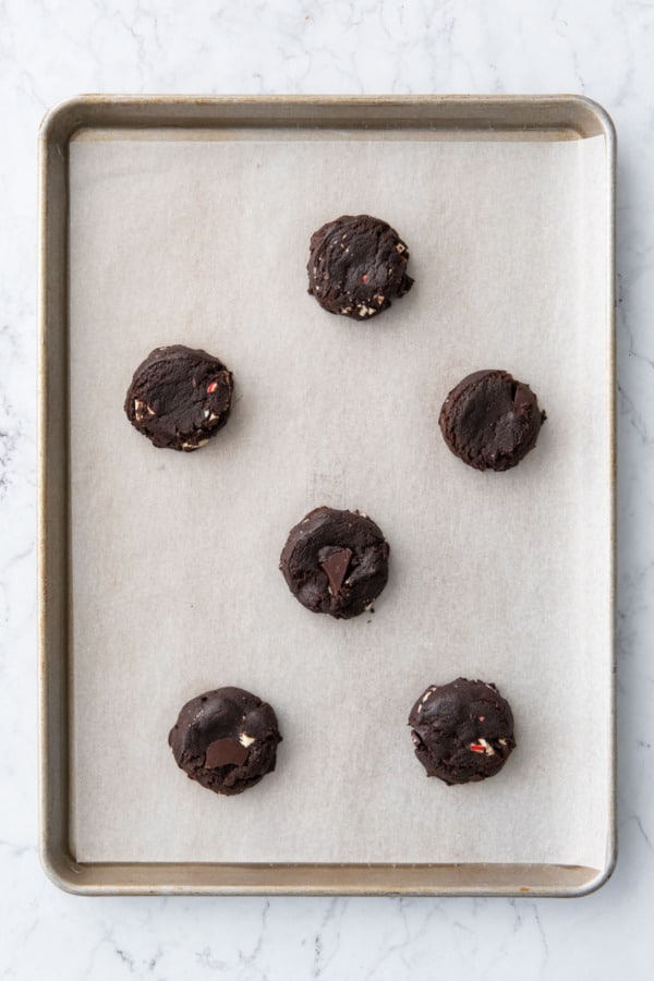 Cookie dough pucks arranged on a parchment lined baking sheet.