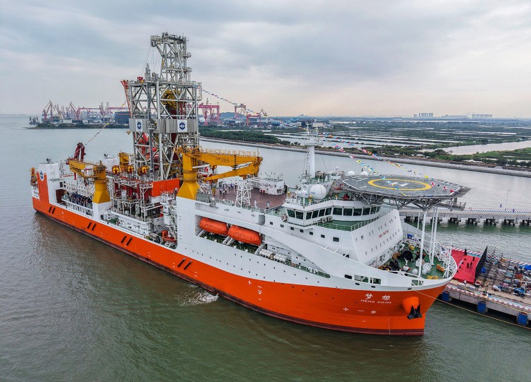 An aerial drone photo shows the orange and white Meng Xiang deep-ocean drilling vessel while docked.
