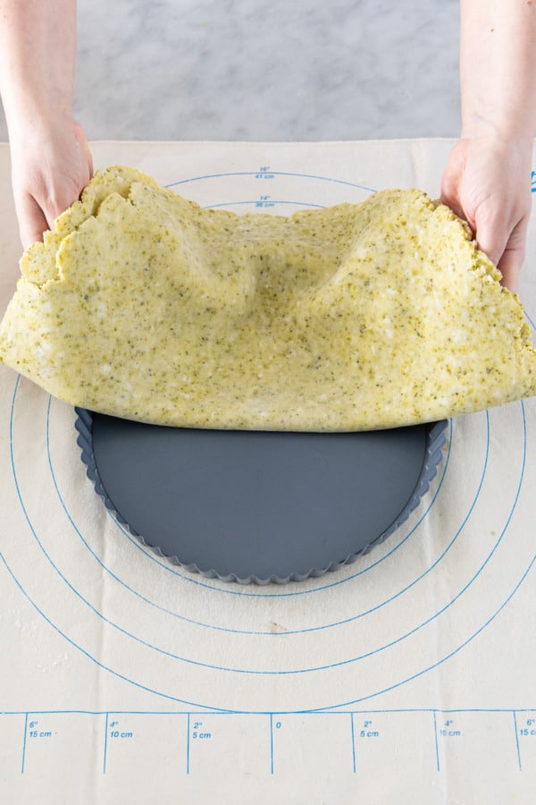 Draping the rolled tart crust into a 9-inch tart pan with removable bottom.