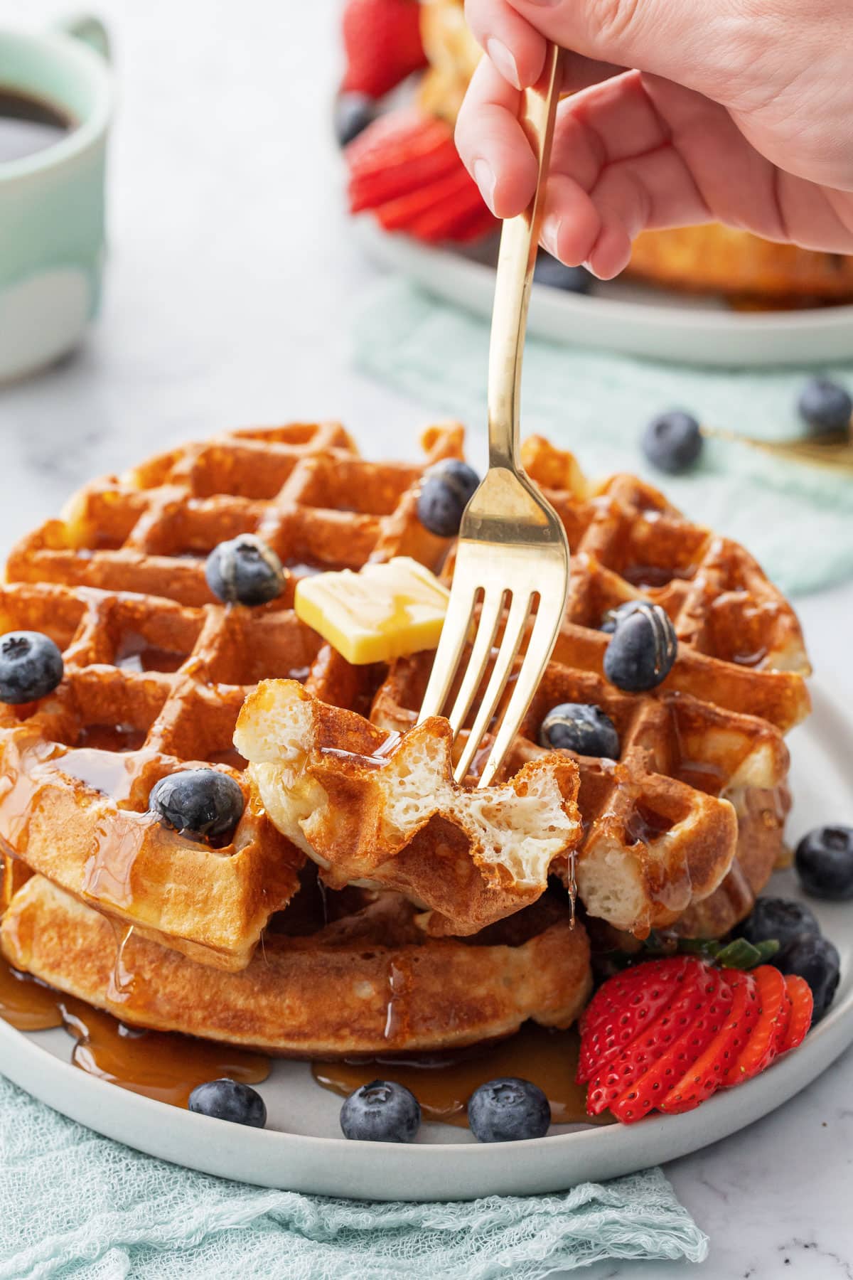Fork lifting a bite of sourdough discard waffle, showing the fluffy interior texture.